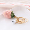 A handmade crochet strawberry and leaf keychain pendant with a gold-colored chain.