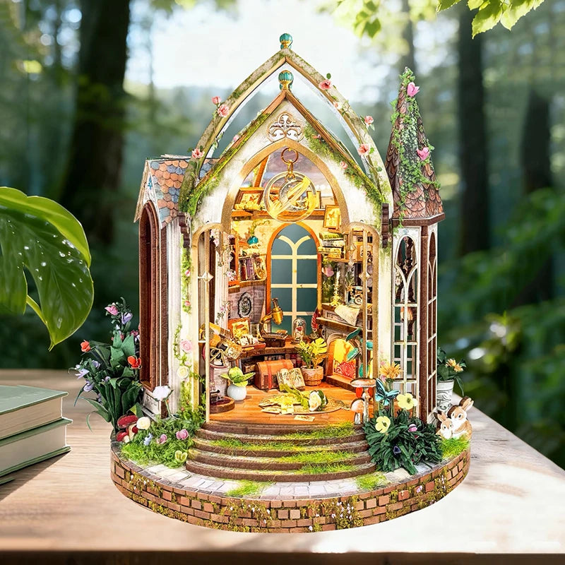A detailed diorama of a wooden floral book nook kit featuring an arched window and miniature landscape.