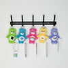 A collection of colorful Care Bears plush keychains hanging from a black rack.