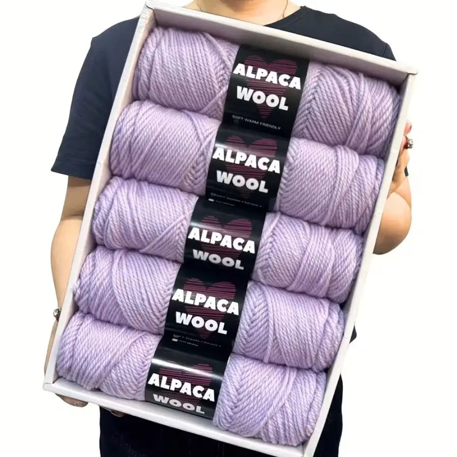 A box containing five skeins of purple alpaca wool yarn for knitting and crochet projects.