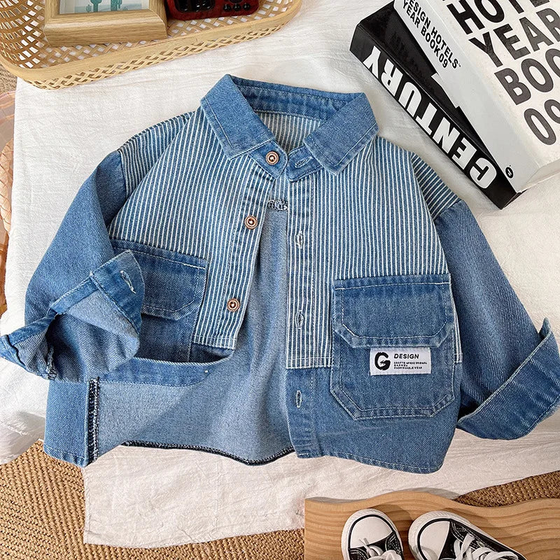 A blue and white striped denim jacket laid flat on a white cloth next to a book.