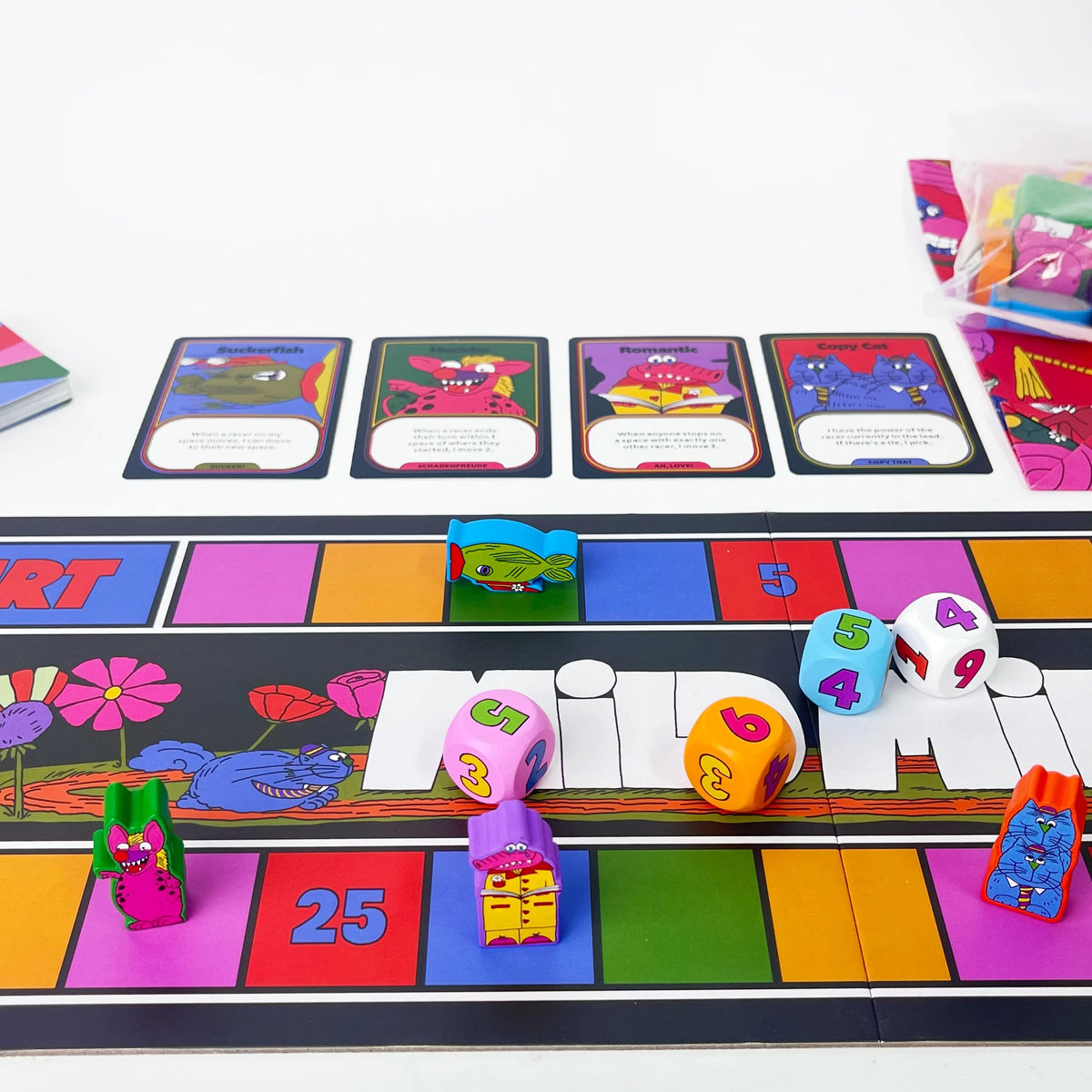 A board game setup showing colorful racing tiles, plastic tokens, and game components for a magical athlete theme.
