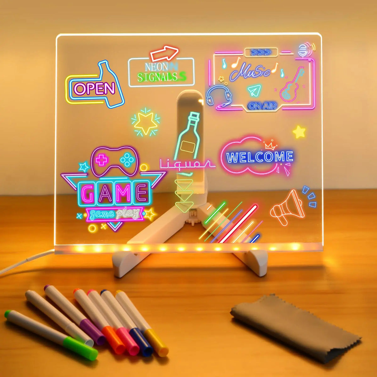 An LED acrylic message board displaying neon signs and a game theme, with several colored pens laid out nearby.