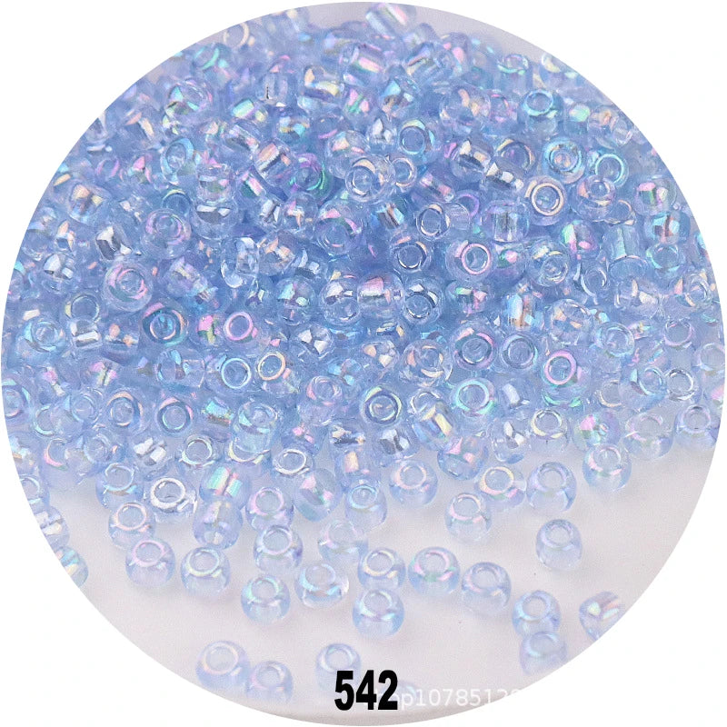 A pile of colorful round loose glass seed beads in various shades of blue and purple for jewelry making