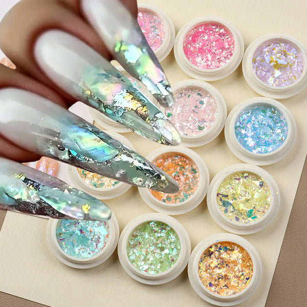 En samling iriserande opal- och sjöjungfrubaserade nagelglitter i små krukor på en ljus bakgrund.