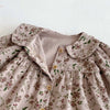 A light pink floral print baby girl jumpsuit with a doll collar and long sleeves.