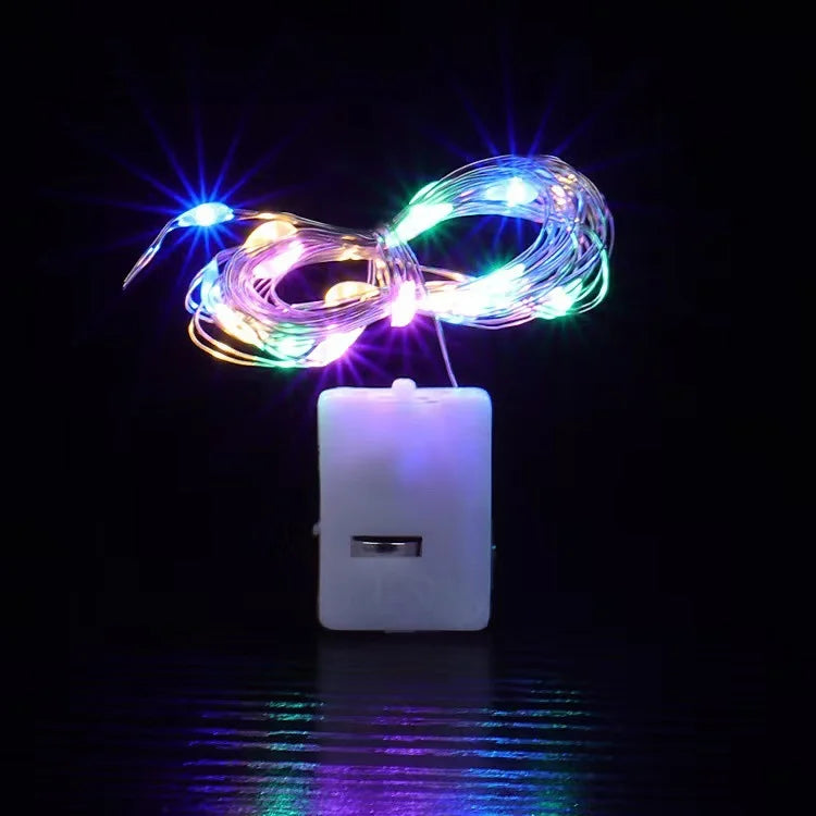 Battery-powered fairy lights glowing in multiple colors and modes against a dark background.