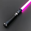 A premium metal lightsaber with a glowing pink blade is shown diagonally on a dark surface.