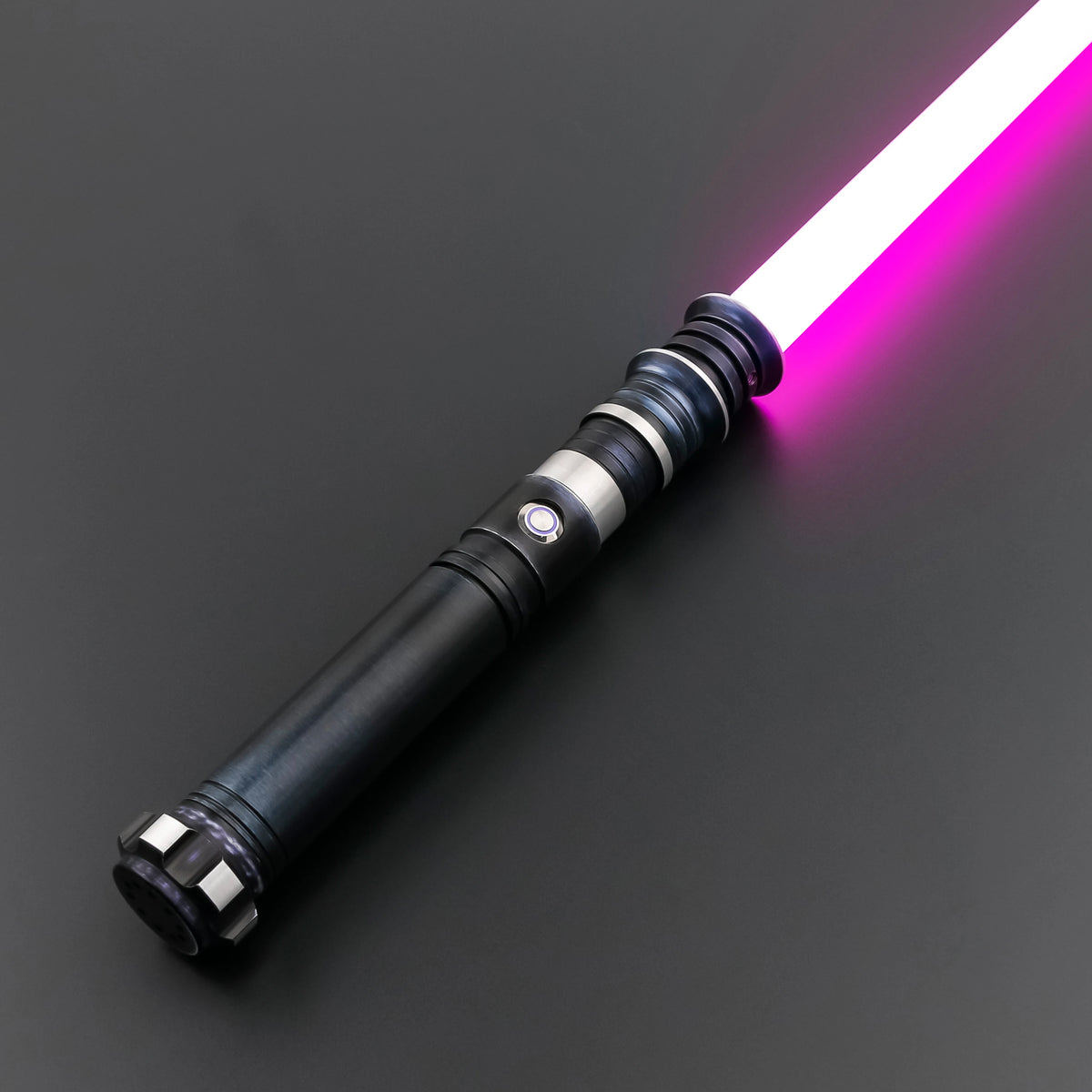 A premium metal lightsaber with a glowing pink blade is shown diagonally on a dark surface.