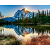 A scenic landscape featuring a mountain reflection on water with a sun flare in the sky.