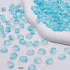Light blue gradient glass beads scattered on a white surface next to a white tool.