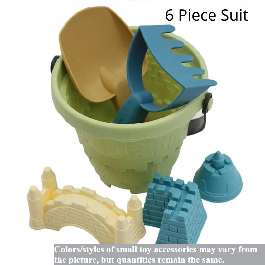 A green plastic bucket contains a beige scoop and a blue shovel, with accompanying sand play accessories.
