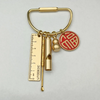 Brass keychain featuring a locking carabiner clip and a round red and gold emblem.