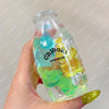 A hand holds a clear bottle filled with colorful squishy milk bottle stress balls for sensory relaxation.