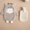 A gray plush toy shaped like a baby goat with horns and a smiling face next to a white hot water bottle.