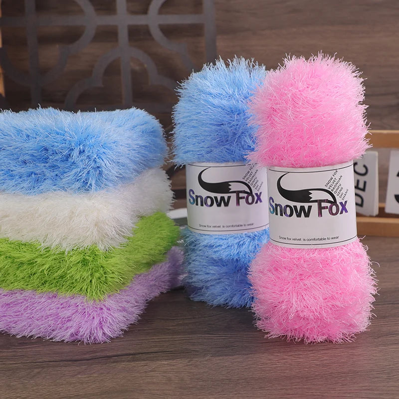 A collection of brightly colored chunky faux fur yarn skeins in blue, pink, and green stacked on a wooden surface.