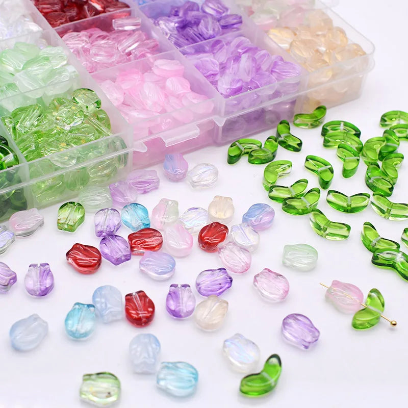 A collection of gradient colored glass beads in various shades of green, pink, purple, and clear are displayed in a plastic c