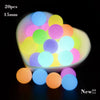 A collection of glow-in-the-dark silicone beads in various colors are displayed in a white dish.