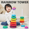 A toddler is playing with a colorful rainbow tower made of stacking rings and a white rod.