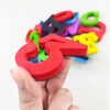 A hand holds a colorful magnetic letter and number set, showing various shapes in red, blue, green, and yellow.