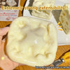 A hand holds a soft, pale yellow cheese cube stress ball with visible indentations.