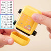A hand holds a yellow math roller stamp showing addition and subtraction problems on a sheet of paper.