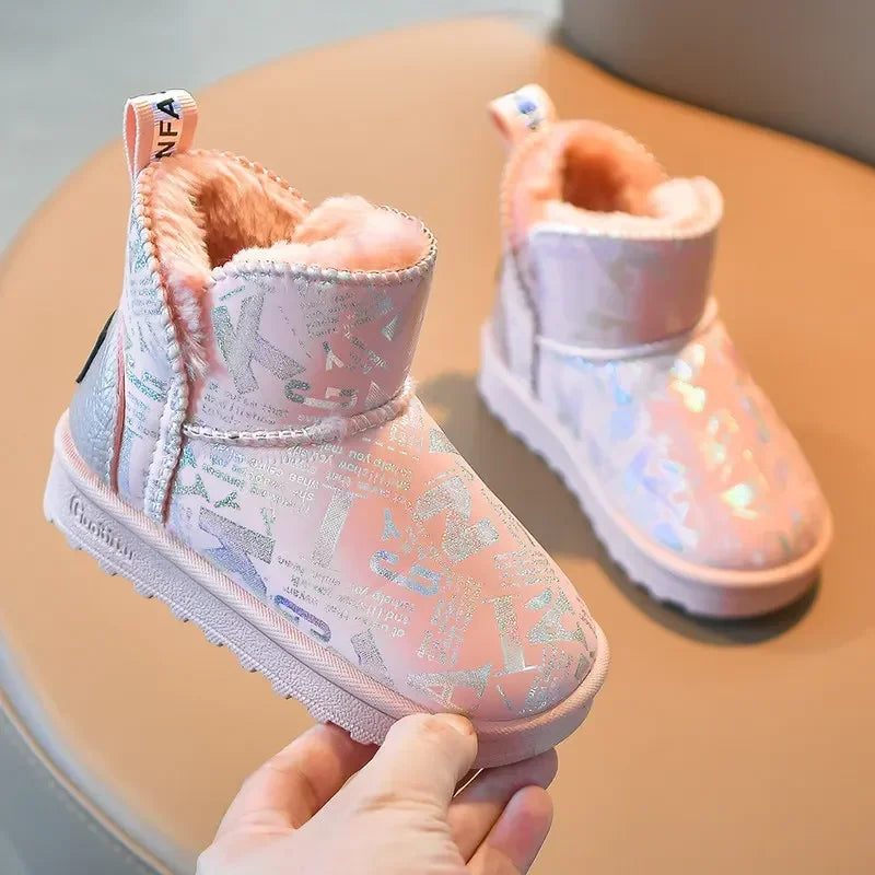 A hand holds a pink winter snow boot with a fluffy sherpa lining and a glittery pattern on the toe.