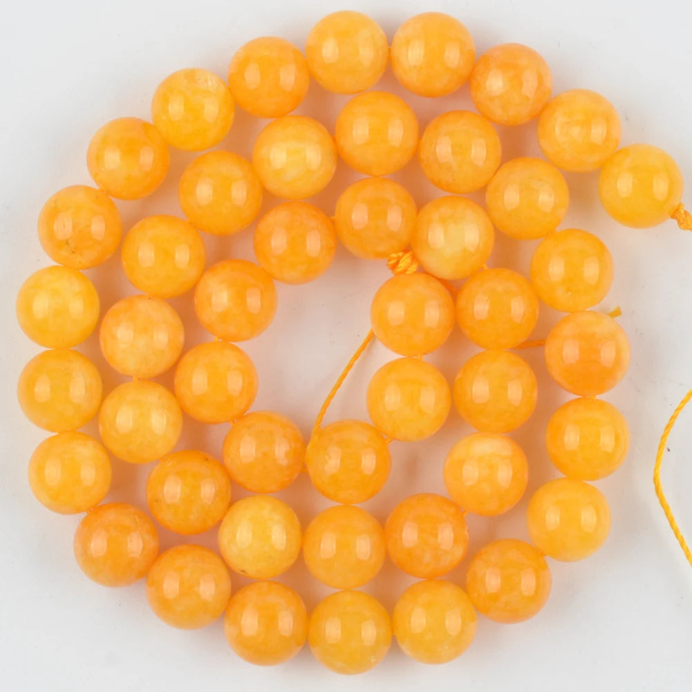 A cluster of small, round, translucent orange beads made from natural sea sediment jasper and turquoise for jewelry making.