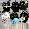 A collection of cute plush black cat keychain charms with various eyes and accessories hanging on a wire.