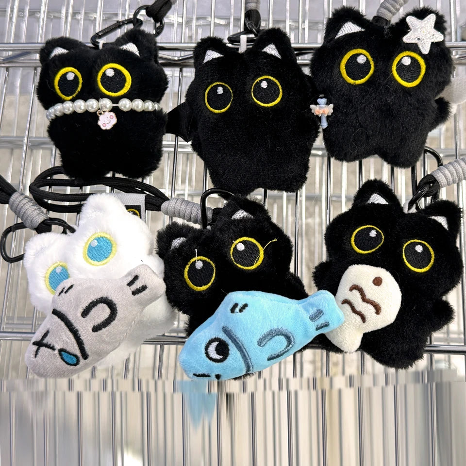 A collection of cute plush black cat keychain charms with various eyes and accessories hanging on a wire.