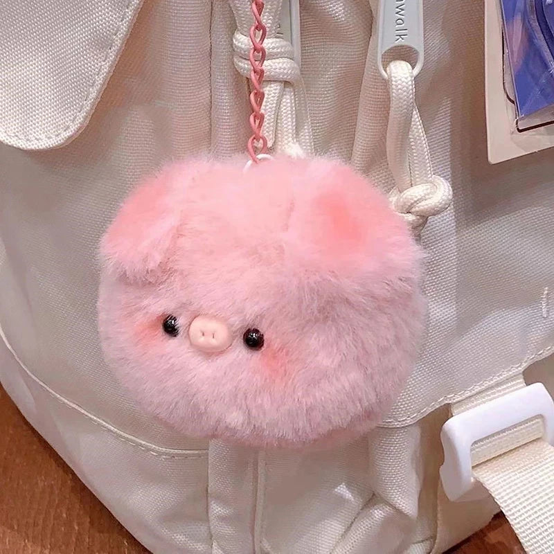 A pink fluffy plush pig keychain attached to a white fabric bag.