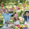 A child is joyfully holding up a collection of assorted mini animal plush toys and keychains outdoors.
