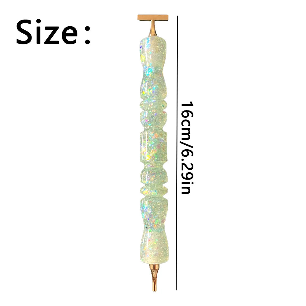 A long, clear glass pen with an iridescent, glittery finish and a gold tip, shown vertically.