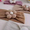 A close-up of floral elastic baby headbands in beige and white knitted fabric.