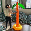 An oversized orange inflatable palm tree with green fronds stands on a yellow base in an indoor setting.