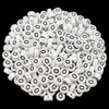 A pile of small white acrylic alphabet letter beads for jewelry making