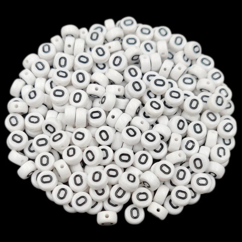 A pile of small white acrylic alphabet letter beads for jewelry making
