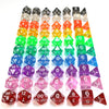 A collection of acrylic dice in various colors and shapes arranged in a grid.