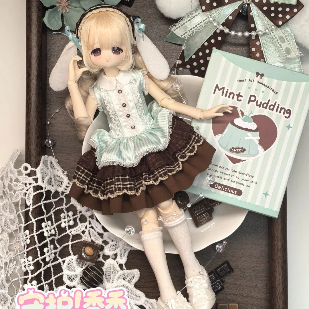 A collectible figure of a girl with blonde hair and light blue clothing is displayed on a wooden background.