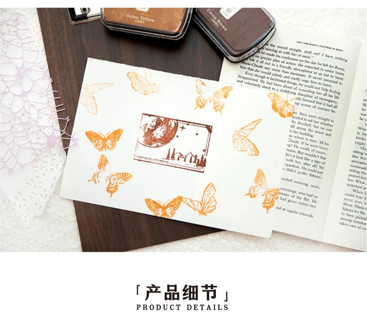 A vintage craft oil-based ink pad featuring an orange butterfly design on a white card, set against a dark wooden background.