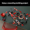 A red and black 1:8 scale open-wheel racing car building kit with many small parts scattered on a dark surface.