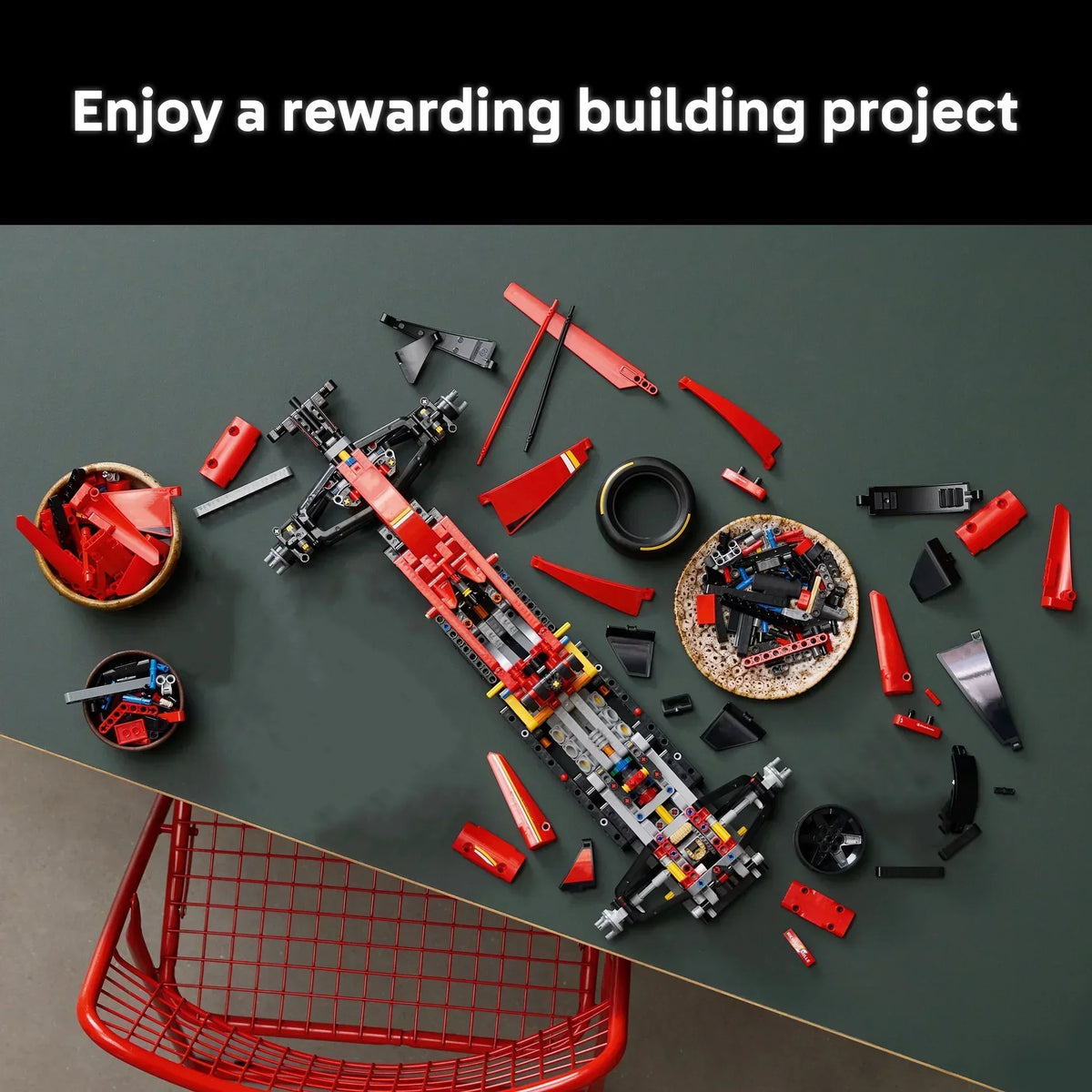 A red and black 1:8 scale open-wheel racing car building kit with many small parts scattered on a dark surface.