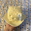A white cheese wedge squishy stress relief toy resting on a light yellow plate.