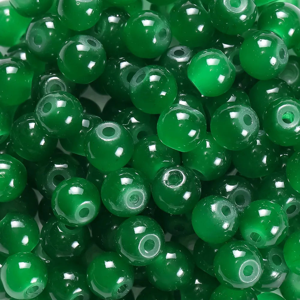 A close-up view of small, round, green glass beads for DIY jewelry making.