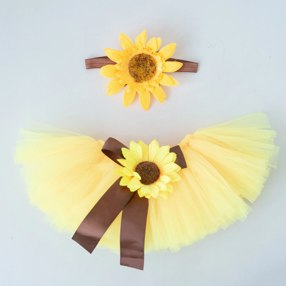 A yellow tulle skirt and headdress set featuring a large sunflower decoration.