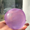 A hand holds a smooth, translucent lavender stress ball made of resin.