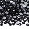 A close-up view of black glass crystal hot fix rhinestones scattered on a white background.