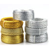 Three spools of flexible aluminum craft wire in gold and silver colors stacked on a white background