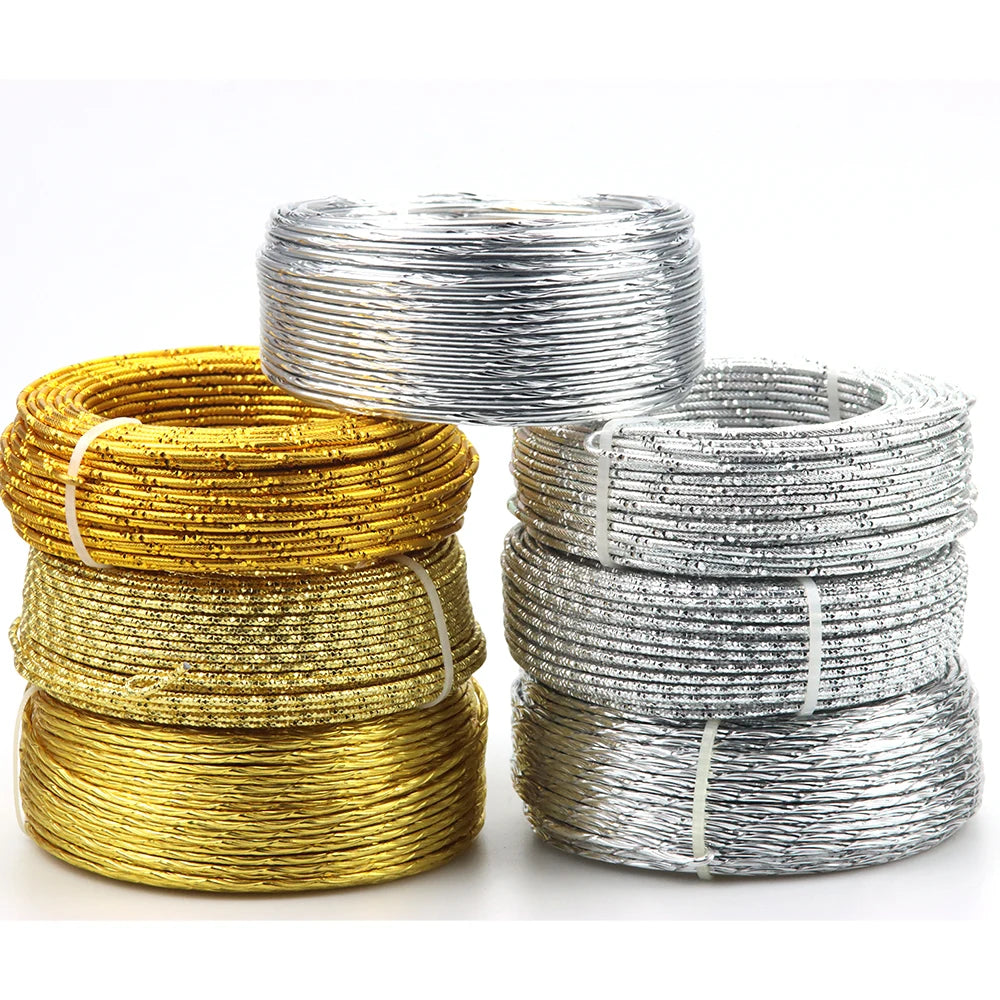 Three spools of flexible aluminum craft wire in gold and silver colors stacked on a white background