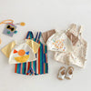 Colorful striped kids overalls with a raindrop print and a yellow shirt lying on a white surface.